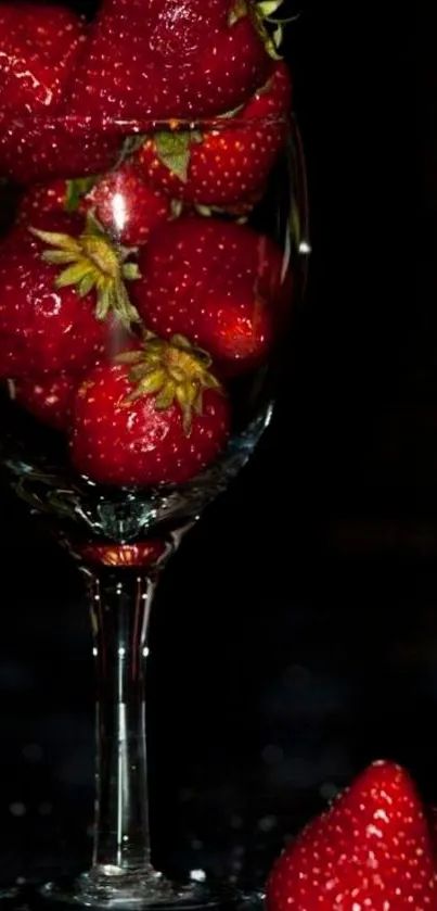 Fresh strawberries in a wine glass against a dark background.