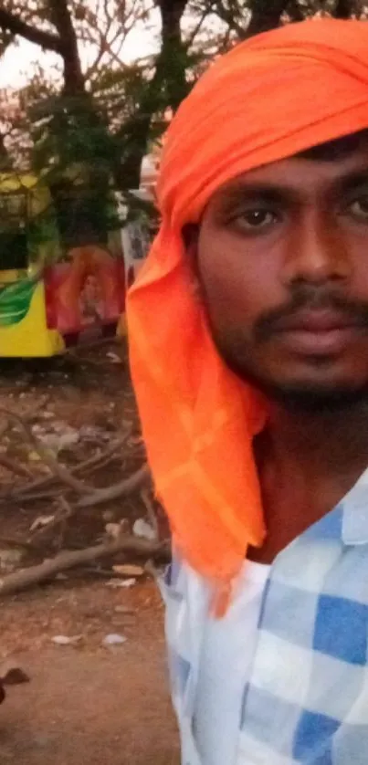 Man wearing orange headscarf in street scene.