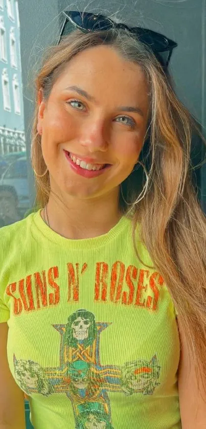 Woman wearing a lime green graphic tee, smiling outdoors.