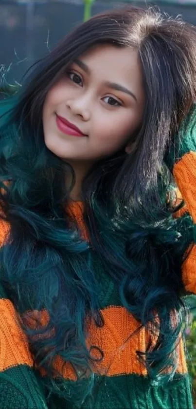 Portrait of a smiling woman with colorful sweater and vibrant hair.