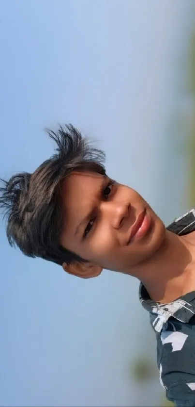 Young man smiling against blue sky background.