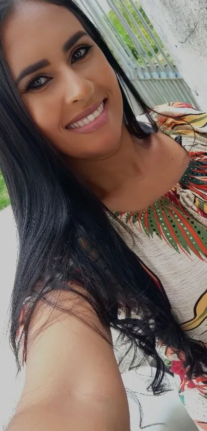 Smiling woman in a tropical dress, outdoor setting.