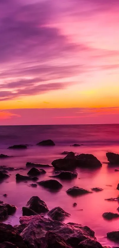 A vibrant sunset over a rocky beach with purple and pink hues.