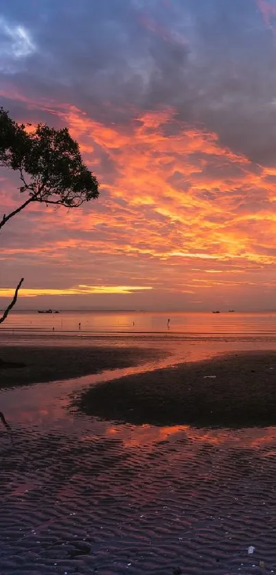 A vibrant sunset over a tranquil beach with glowing orange and pink skies.