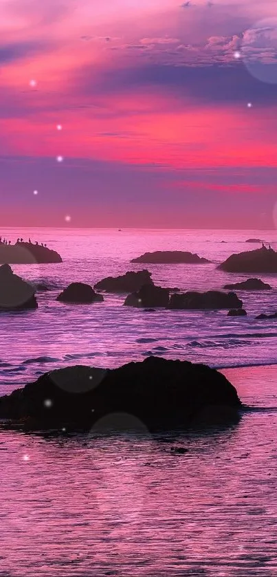 Vibrant sunset over a rocky ocean beach with pink and purple hues.