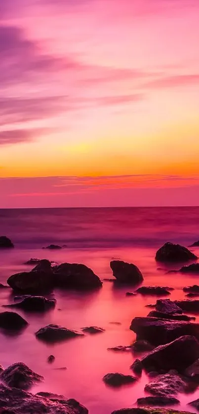 Vibrant sunset over coastal rocks with pink and orange hues.