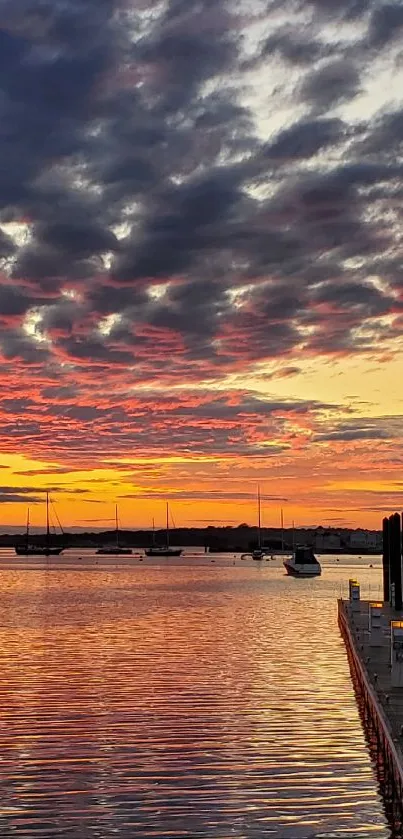 Sunset over harbor with vibrant colors reflecting on water.