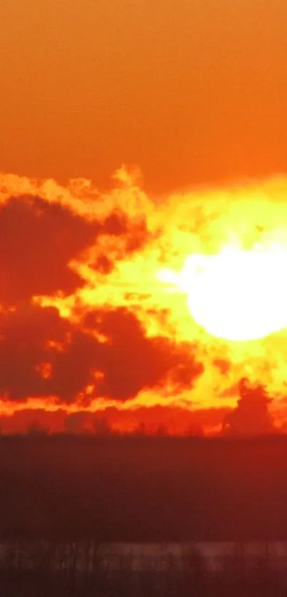 Sun setting over horizon with vibrant orange clouds.