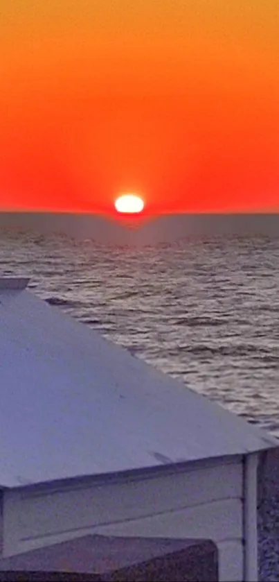 Vibrant orange sunset over the ocean with serene horizon.