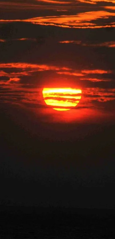 Fiery orange sunset over a calm ocean with dark clouds.