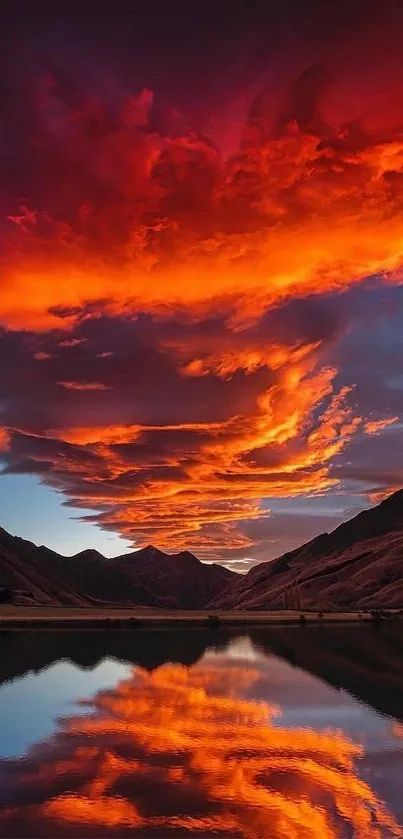 Fiery sunset clouds reflect on a tranquil lake surrounded by mountains.