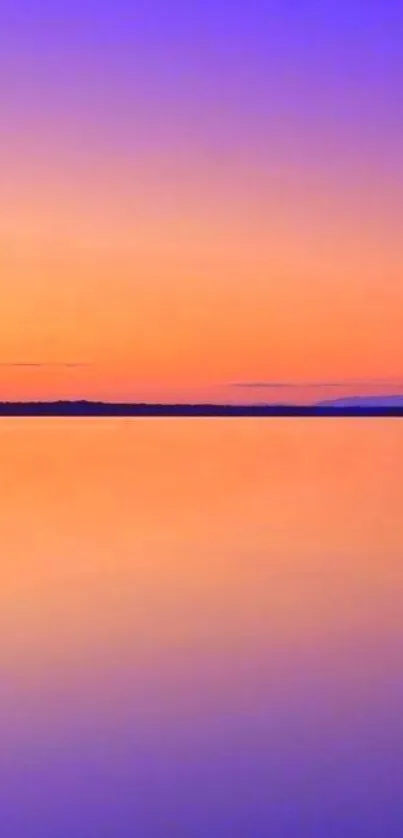 Vibrant sunset with orange and blue hues reflecting on calm water.