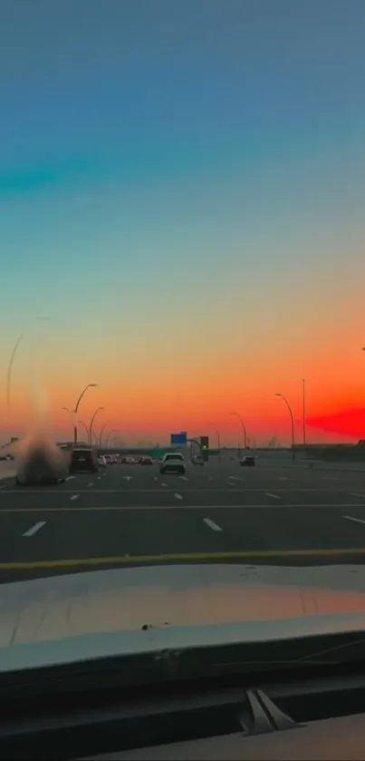 A road view at sunset with vibrant orange sky.