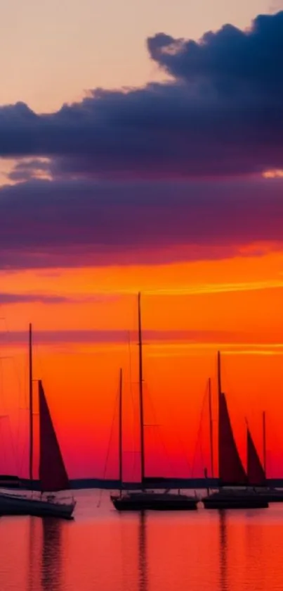 Silhouetted sailboats against a vibrant orange sunset sky.