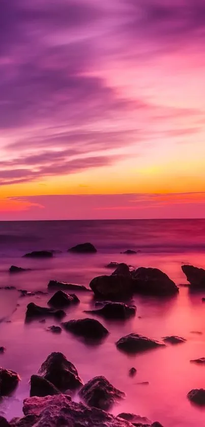 Vibrant sunset over rocky seascape with magenta and orange hues.