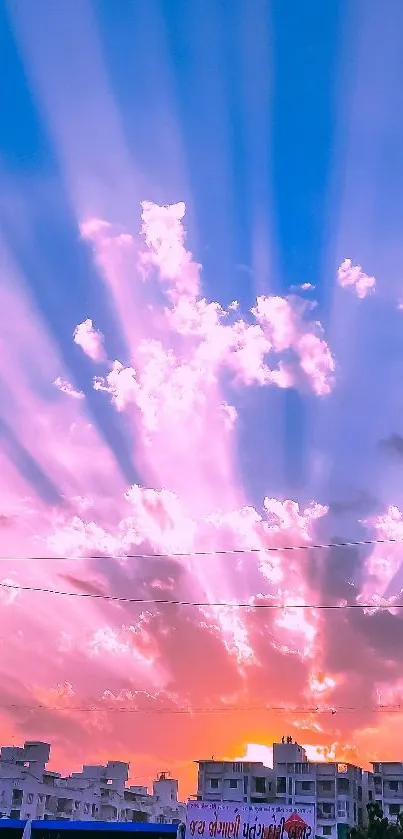 Pink and blue sunset sky with sun rays over cityscape.