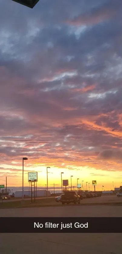 Vibrant sunset sky with orange clouds and purple hue over cityscape.