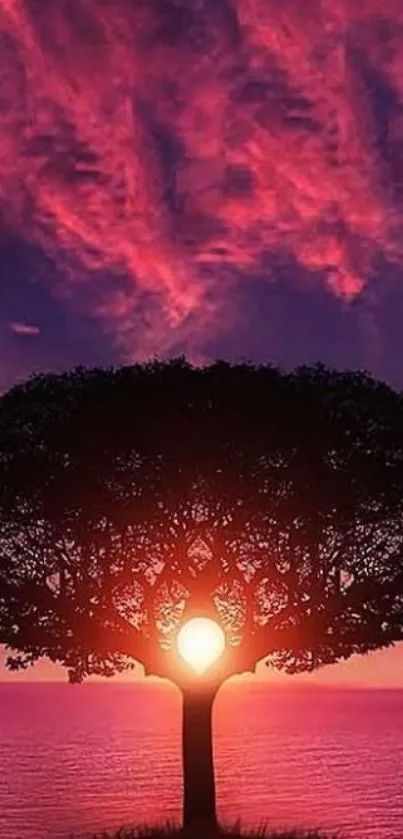 Silhouetted tree against vibrant sunset over ocean.