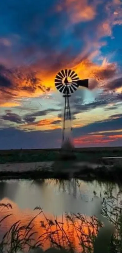 Windmill silhouetted against vibrant sunset sky reflected in water.