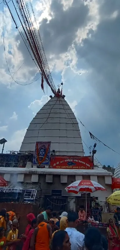 Temple with vibrant crowd under a dramatic sky.