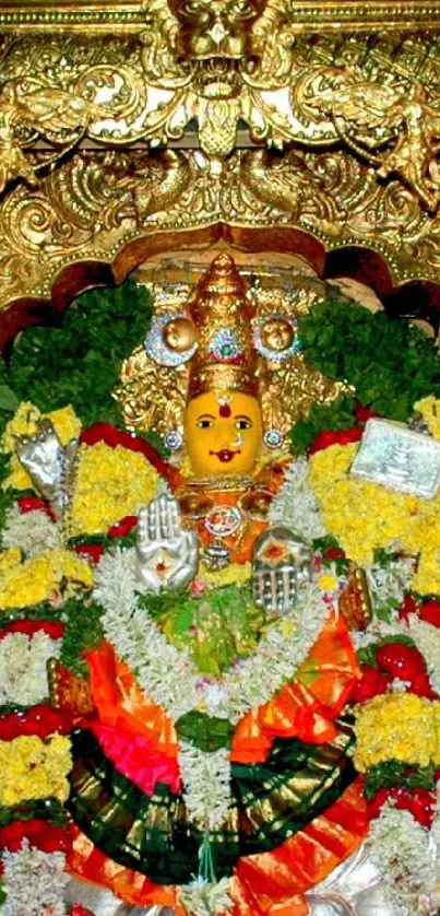 Intricate temple deity adorned with gold and colorful garlands.