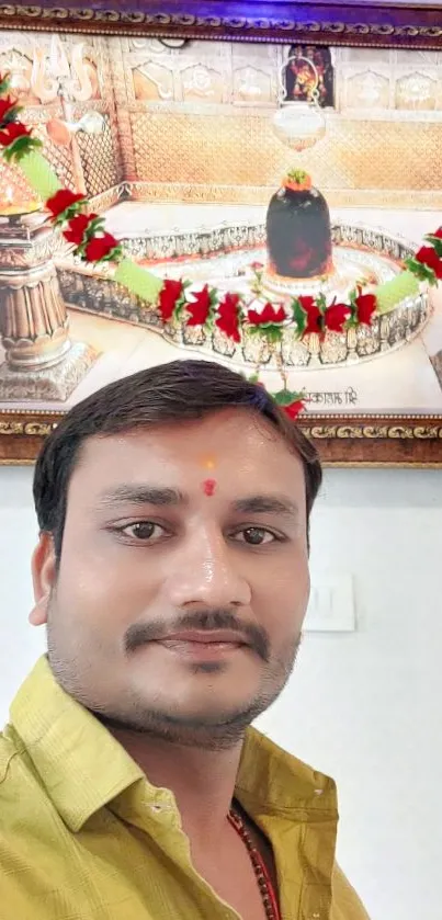 Man posing in front of a framed temple decoration.