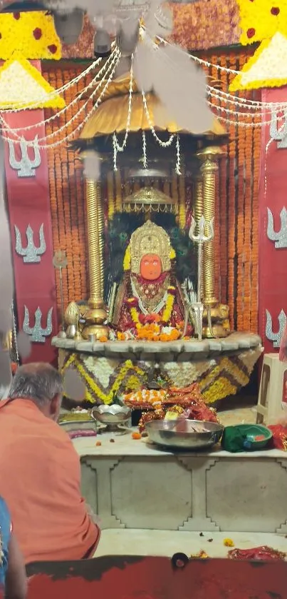 Orange adorned temple shrine with deity and vibrant decor.