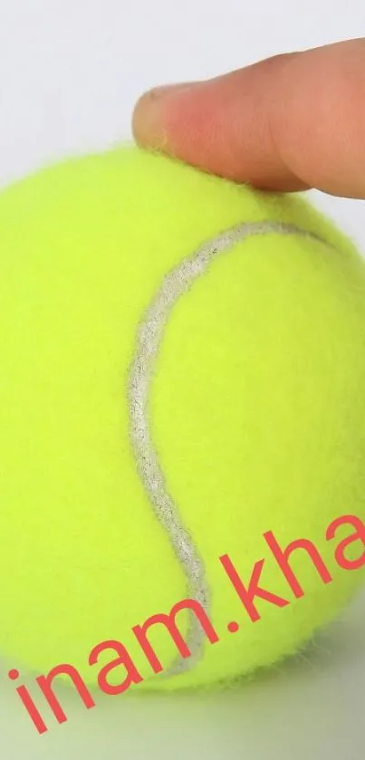 Close-up of a vibrant yellow tennis ball held by two fingers.