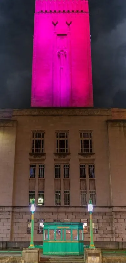 Night view of a glowing pink tower against a dark, cloudy sky.