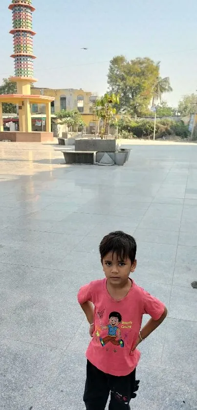 Child in vibrant town square with colorful tower.