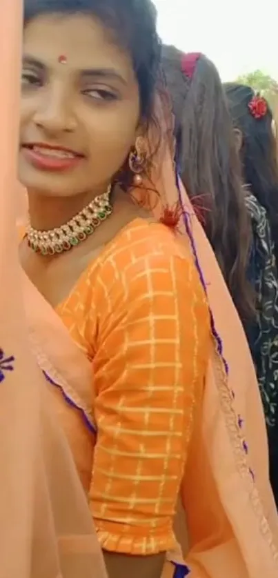 Woman in vibrant traditional attire with peach tones.