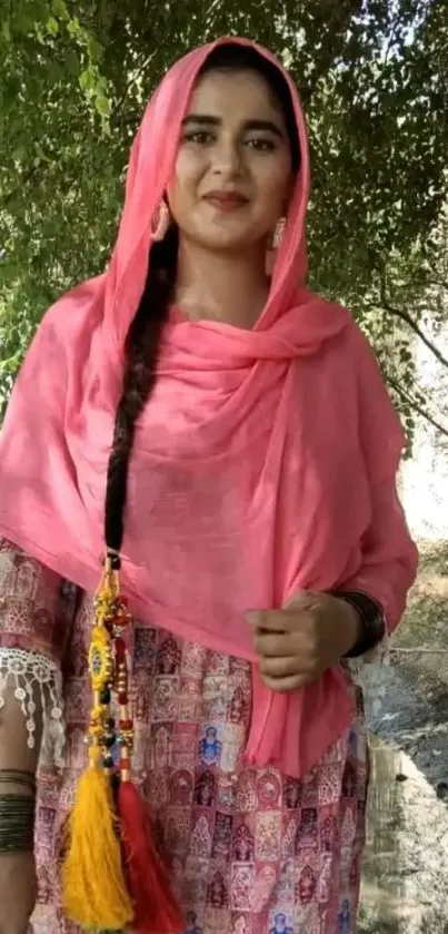 Woman in traditional pink attire with a nature background.