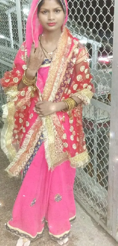 Woman in red and pink traditional saree with ornate designs.