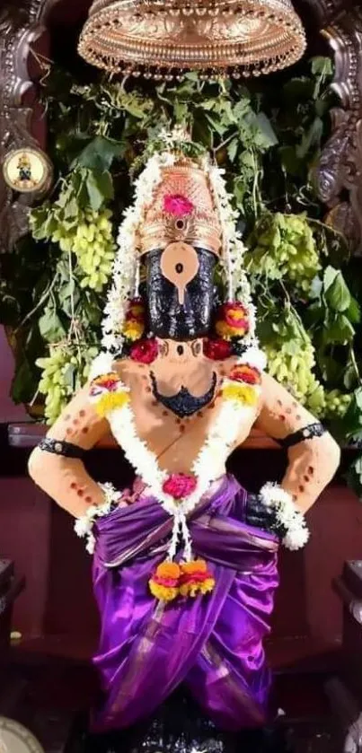 Traditional Indian deity adorned with floral garlands and vibrant purple attire.