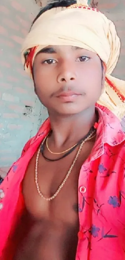 A young person in traditional clothing with a vibrant red shirt and head wrap.