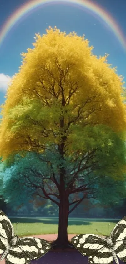 Vibrant tree with yellow leaves beneath a rainbow and butterflies on grass.