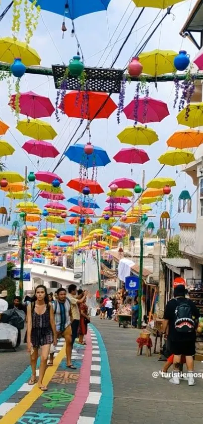 Vibrant street with colorful umbrellas overhead and people walking down.