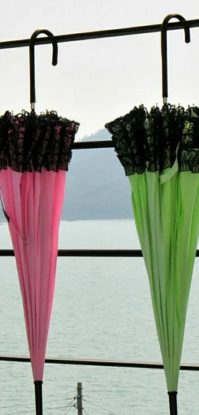 Vibrant pink and green umbrellas hanging by the sea.