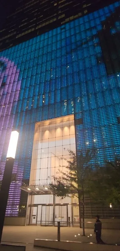 Vibrant skyscraper at night with blue and purple lights.