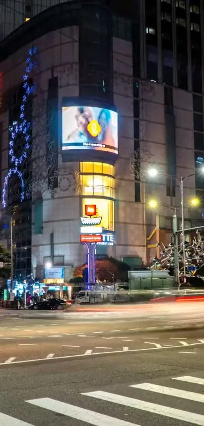 Night view of a city intersection with bright lights and tall buildings.