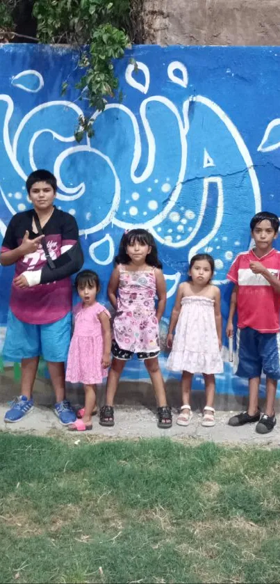 Children standing by vibrant blue graffiti wall.