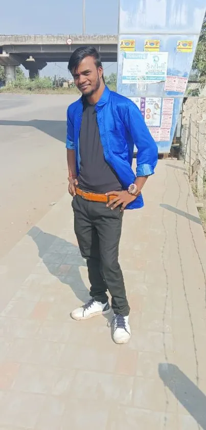 Stylish individual in blue shirt with urban background.