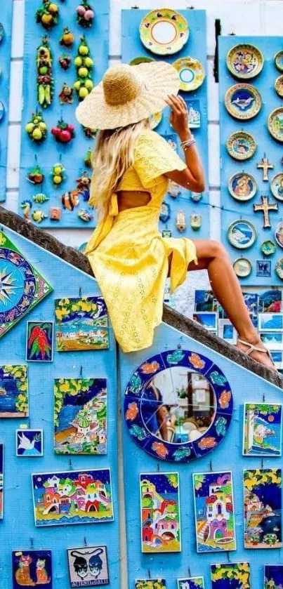 Woman in yellow dress sitting on vibrant blue art wall.