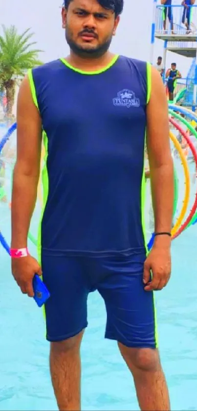 Man stands at water park with slides and pool activities.