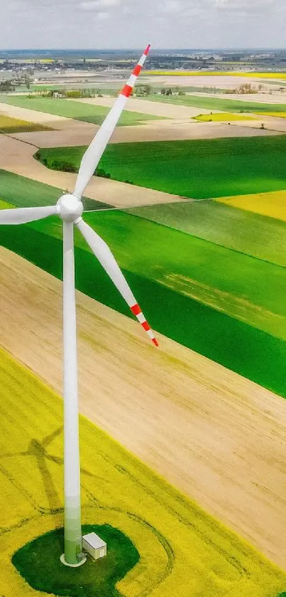 Aerial view of wind turbine in green fields under a cloudy sky.