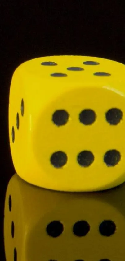 Yellow dice against black backdrop with reflection.