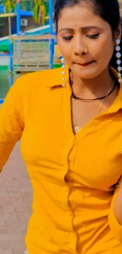 Portrait of a woman in a mustard yellow shirt with colorful background.