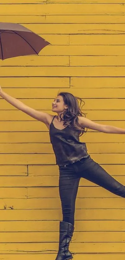 Joyful woman with umbrella on vibrant yellow wall.