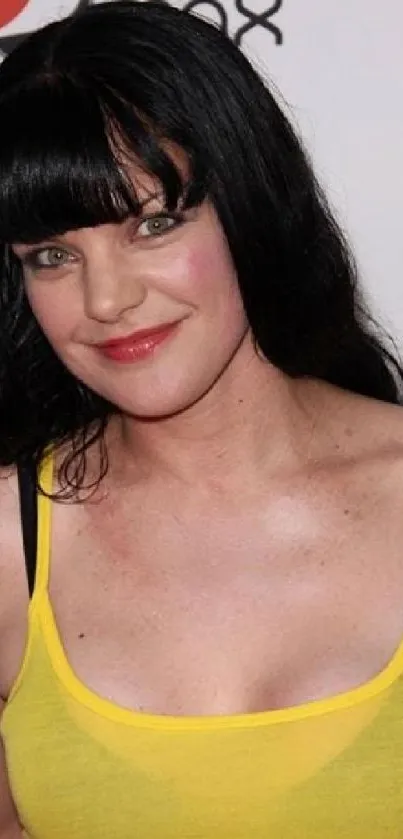 Smiling woman in bright yellow top against white background.