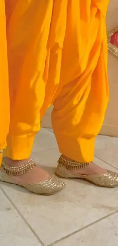 Vibrant yellow Punjabi suit with gold desi jutti on a light tile floor.